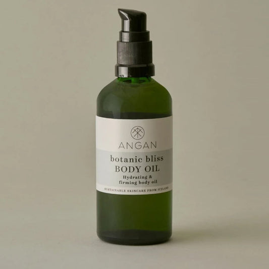 A dark green glass bottle of Angan Westfjords Botanic Bliss Body Oil against a grey-green background.