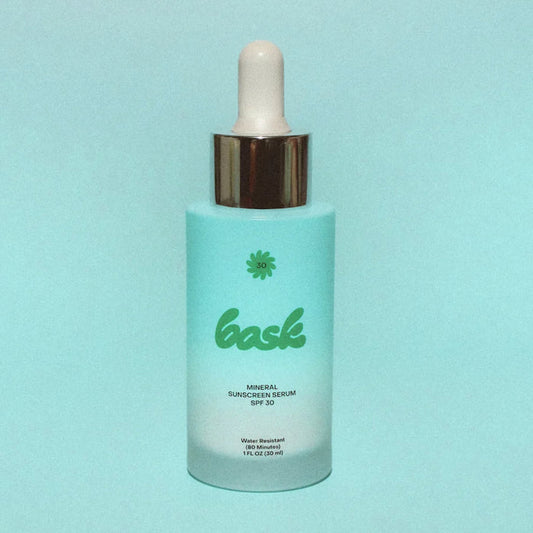 Bask SPF 30 Mineral Sunscreen Serum bottle on a blue background.