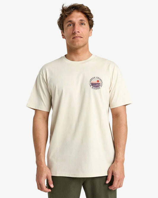 Man wearing a beige billabong rockies t-shirt with a graphic design on a white background