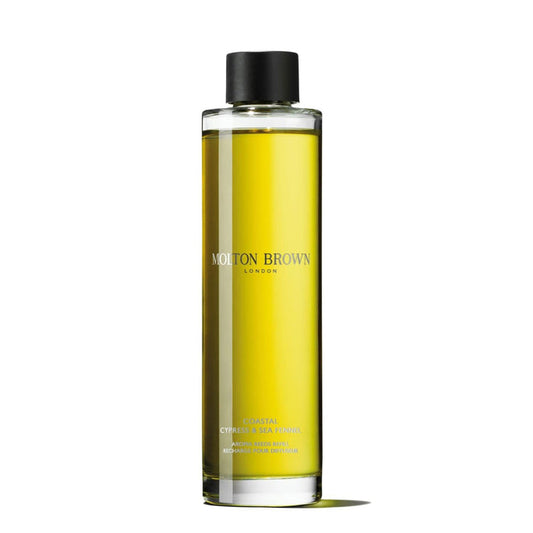 A clear glass bottle containing yellow liquid with Molton Brown branding, refill for aroma reeds.