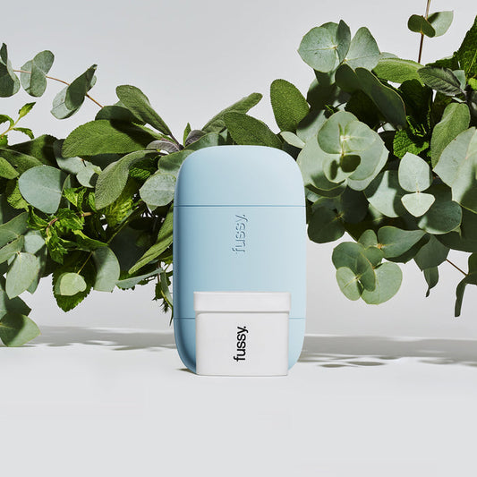 Fussy's Wavy Days natural deodorant starter pack wth Pale Blue case set against a background of ingredients - eucalyptus, sage and mint.